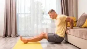 A man performing stretches to relieve back pain at home using an exercise mat.